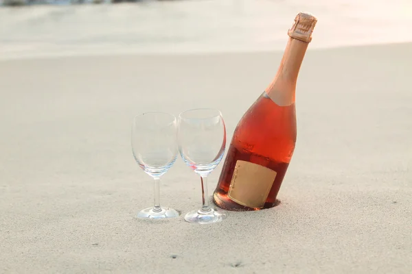 Bottiglia di vino rosso e due bicchieri sulla spiaggia di sabbia bianca — Foto Stock