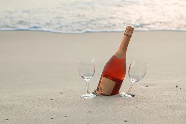 Bottiglia di vino rosso e due bicchieri sulla spiaggia di sabbia bianca — Foto Stock