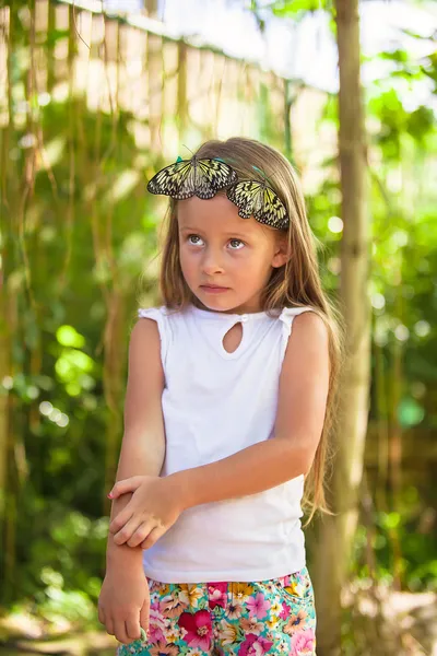 Klein meisje speelt met vlinder in vlinders de tuin — Stockfoto