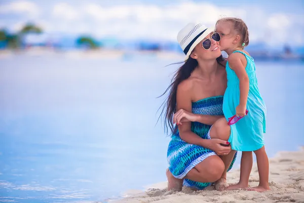 Lilla flickan kysser hennes mor på en vit, tropisk strand — Stockfoto