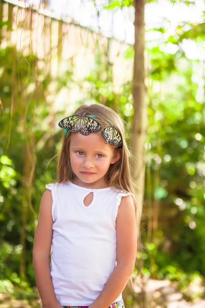 Little adorable girl is playing with butterfly in butterflies garden — Stock Photo, Image