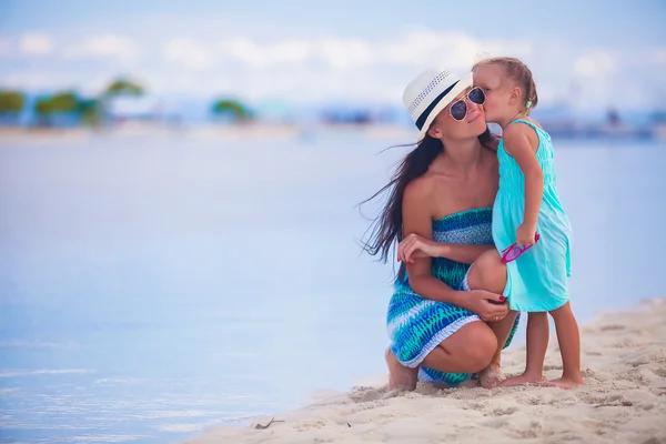 Little girl kissing her beautiful mother on a white tropical beach — Stock Photo, Image