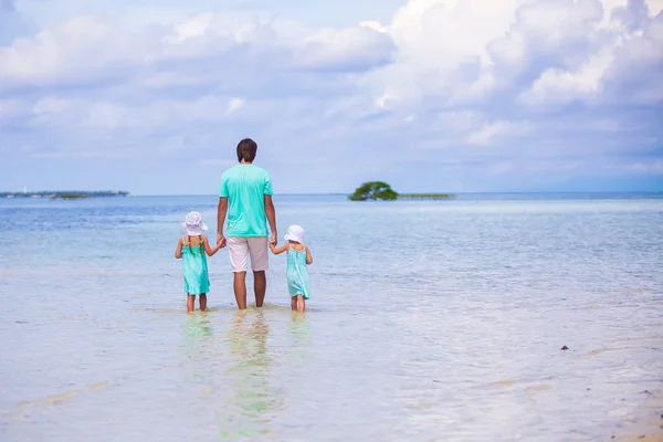 Back view of adorable little girls and young father walking at exotic island