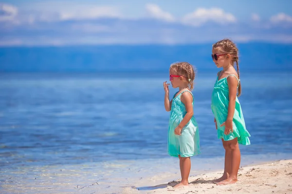 Little adorable girls in turquoise dress on white beach look at the sea — Stock Photo, Image