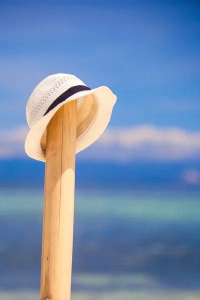 Cappello di paglia alla recinzione di legno sulla spiaggia di sabbia bianca con vista sull'oceano — Foto Stock