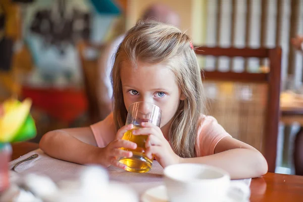 Cute little girl having breakfast and drinking fruit juice — Stock Photo, Image