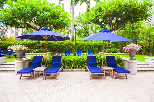 Beach beds with umbrellas near swimming pool in luxury hotel — Stock Photo, Image