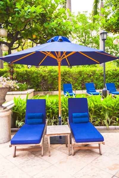Duas cadeiras com guarda-chuvas perto da piscina em hotel de luxo — Fotografia de Stock