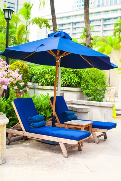 Due lettini blu con ombrelloni vicino alla piscina in hotel di lusso — Foto Stock