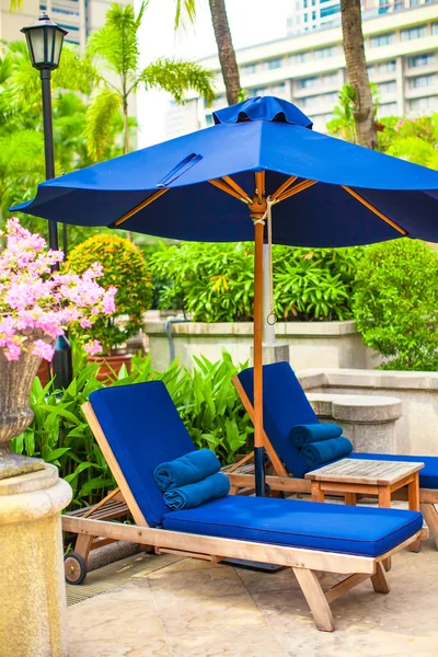 Two blue loungers with umbrellas near swimming pool in luxury hotel — Stock Photo, Image