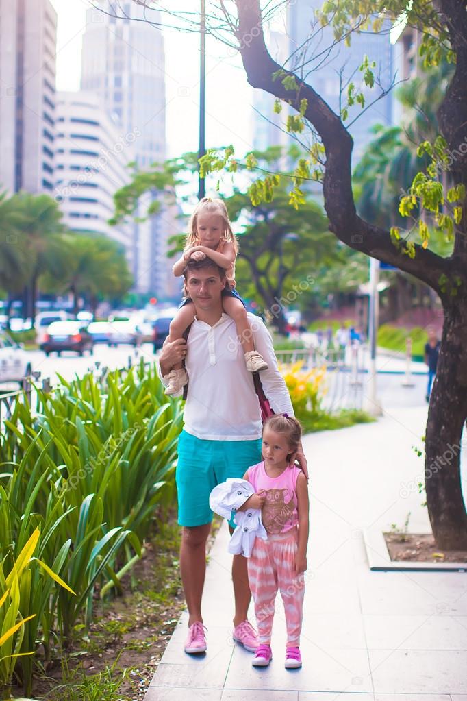 Young father walking with little girls in a big city outdoor