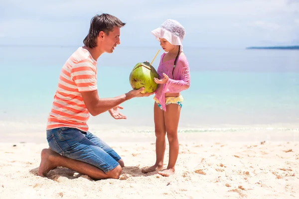 Portrait of cute little girl and young father with coconut milk on exotic beach — Stock Photo, Image