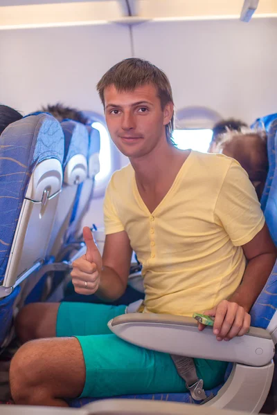 Jonge man in een vliegtuig tijdens de vlucht thums opdagen — Stockfoto