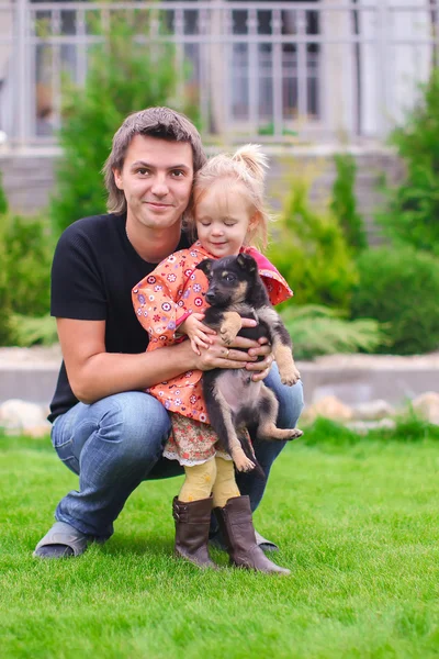 Junger glücklicher Vater und kleines süßes Mädchen mit ihrem Welpen draußen — Stockfoto