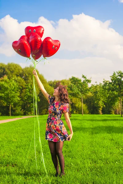 Glad flicka ha kul med röda ballonger utomhus — Stockfoto