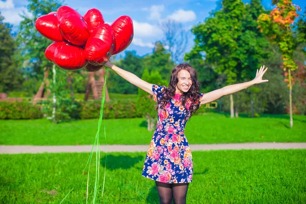 Giovane donna attraente felice in bel vestito divertirsi con palloncini rossi fuori — Foto Stock