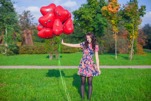 Young happy attractive woman in beautiful dress with red balloons walking outside — Stock Photo, Image