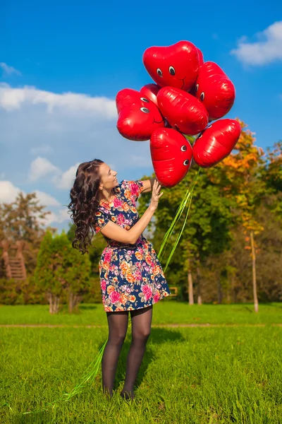 Joven chica feliz en vestido colorido divertirse con globos rojos fuera —  Fotos de Stock