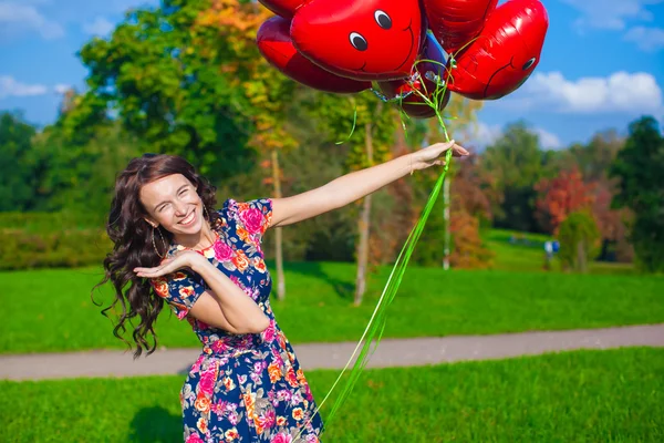 Primer plano de mujer atractiva joven en hermoso vestido con globos rojos —  Fotos de Stock