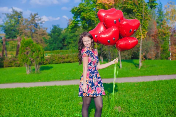 Ung vacker kvinna med röda ballonger promenader utomhus — Stockfoto