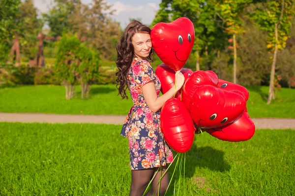 Giovane bella donna con palloncini rossi a piedi all'aperto — Foto Stock