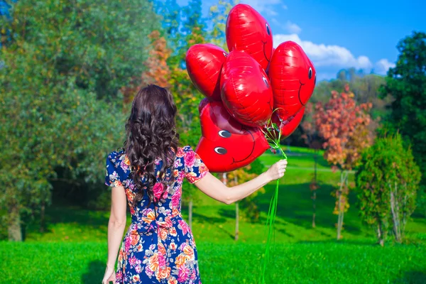 Vista trasera de mujer joven con globos rojos en la mano —  Fotos de Stock