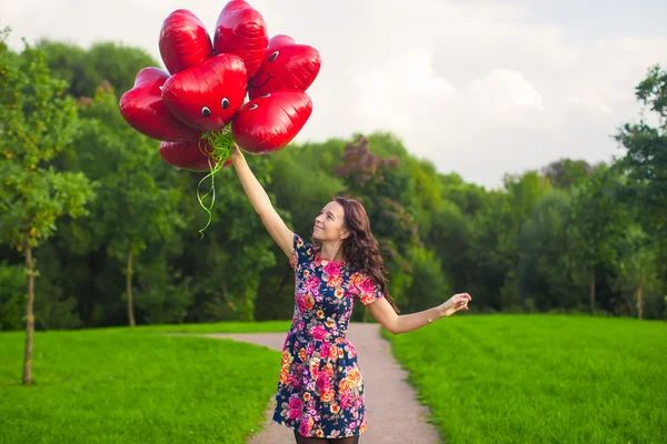 赤い風船の付いた美しいドレスの素敵な少女は、屋外の楽しい時を過す — ストック写真