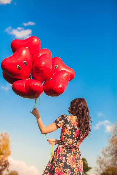 赤い風船手背景青スライで若い女性の背面図 — ストック写真