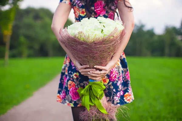 Bela grande buquê rosas brancas nas mãos de uma jovem no vestido colorido — Fotografia de Stock