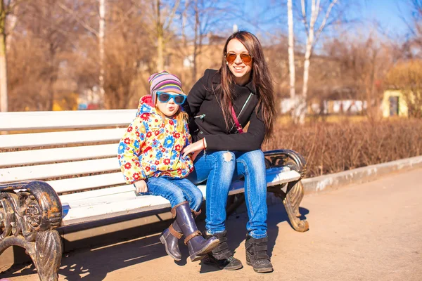 Jonge moeder en beetje blij meisje ontspannen in voorjaar park in zonnige dag — Stockfoto