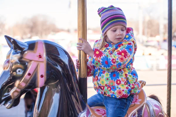 Маленькая счастливая девочка, катающаяся на карусели в парке развлечений — стоковое фото