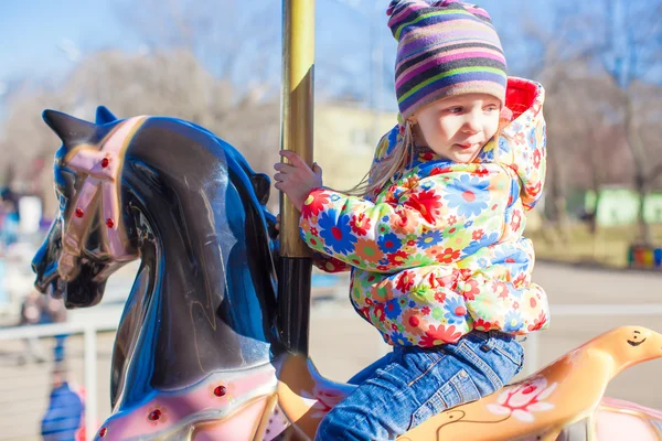 Pequena menina feliz passeio no carrossel em um parque de diversões — Fotografia de Stock