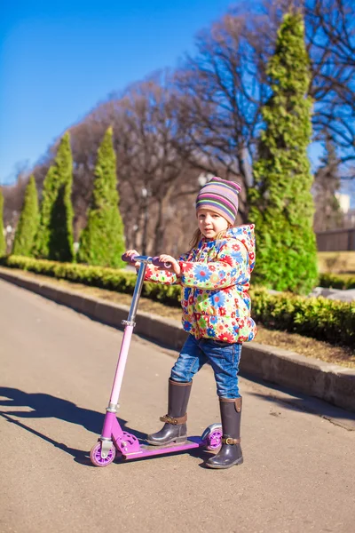 Adorable niña en el scooter en cálido día de primavera — Foto de Stock