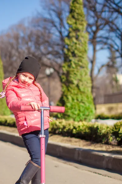 Adorable little girl have fun on the scooter in warm spring day — Stock Photo, Image