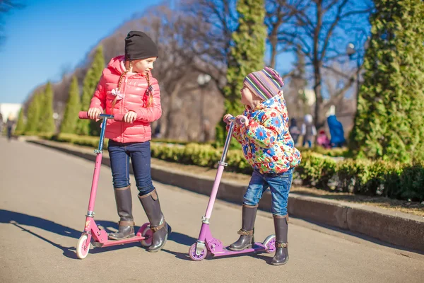 Little beautiful girls with scooter in spring park — Stock Photo, Image