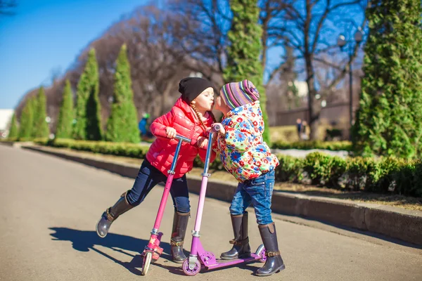 Adorables hermanitas montan scooters en un cálido día soleado de primavera — Foto de Stock