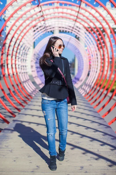 Young happy woman talking on the phone and walking in park — Stock Photo, Image