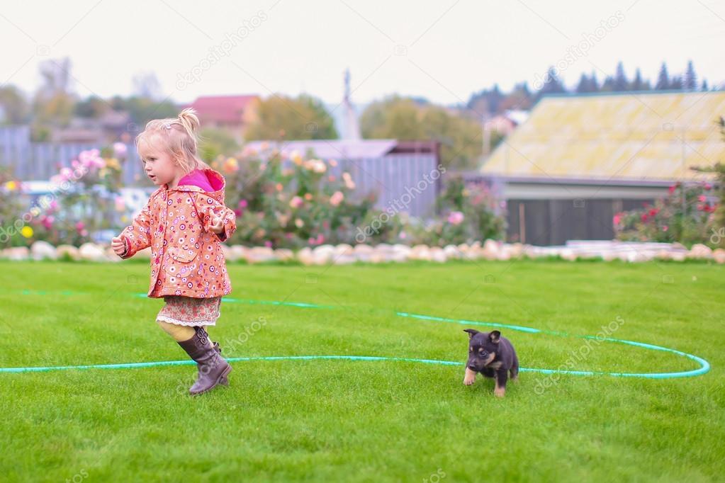 Cute little girl playing with her puppy in the yard