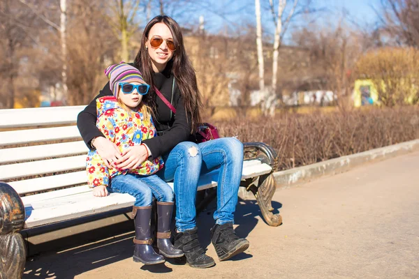 Little cute girl relax with young mother at sunny day in the city — Stock Photo, Image
