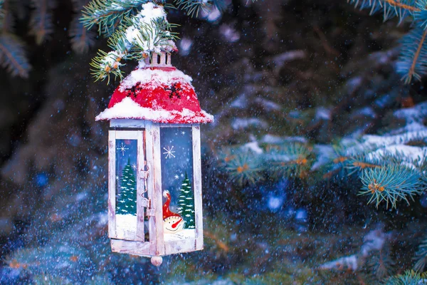 Beautiful red fairytale lantern hanging on snowy fir branch in forest — Stock Photo, Image