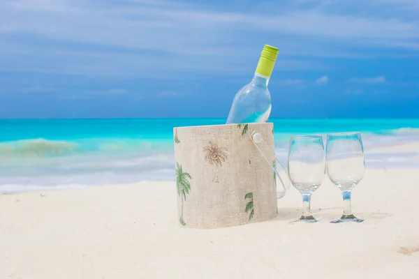 Láhev bílého vína a dvě skleničky na exotické pláži — Stock fotografie