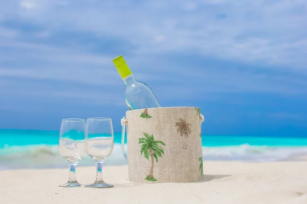 Fles van witte wijn en twee glazen op het exotische zandstrand — Stockfoto