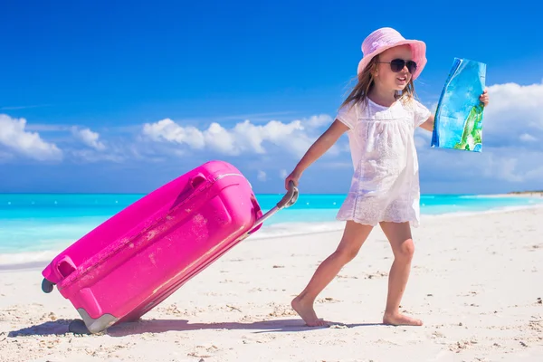 Little adorable girl with big colorful suitcase and a map in hands on tropical beach — Stock Photo, Image