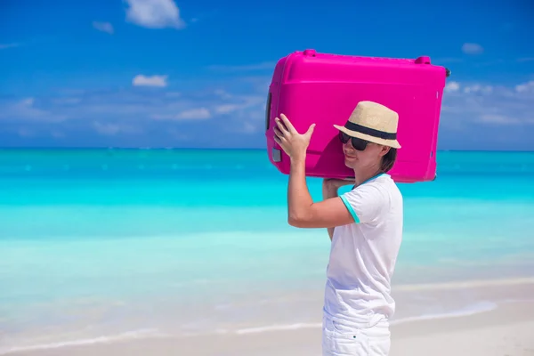 Portret van een jonge man die zijn bagage op het strand — Stockfoto
