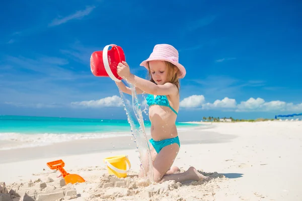 Adorable little girl playing with sand on a perfect tropical beach — Stock Photo, Image