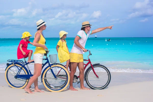 Young family riding bicycles on a tropical beach — Stock Photo, Image