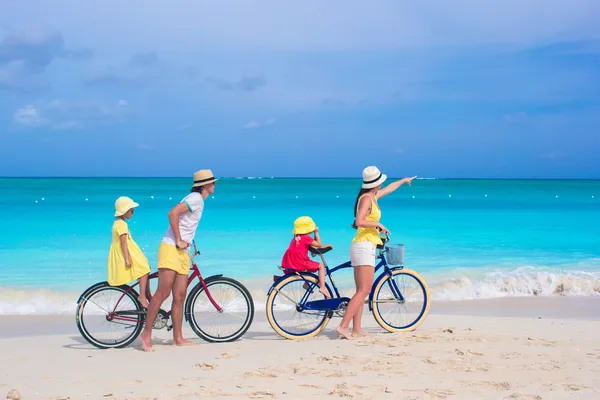 Молодая семья с маленькими детьми катаются на велосипедах на тропическом экзотическом пляже — стоковое фото