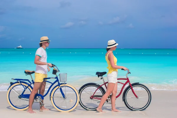Young happy couple riding bikes on white sandy beach — Stock Photo, Image