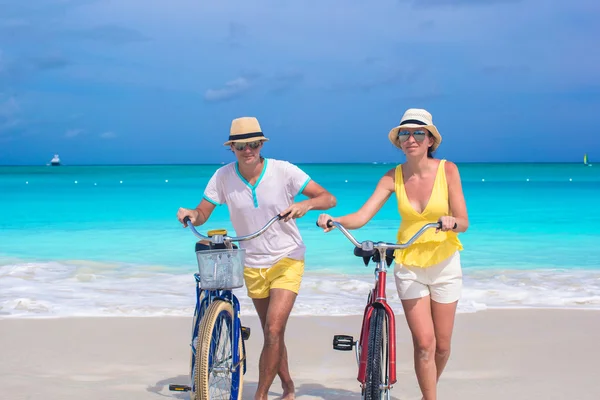 Young happy couple with bikes on white sandy beach — Stock Photo, Image