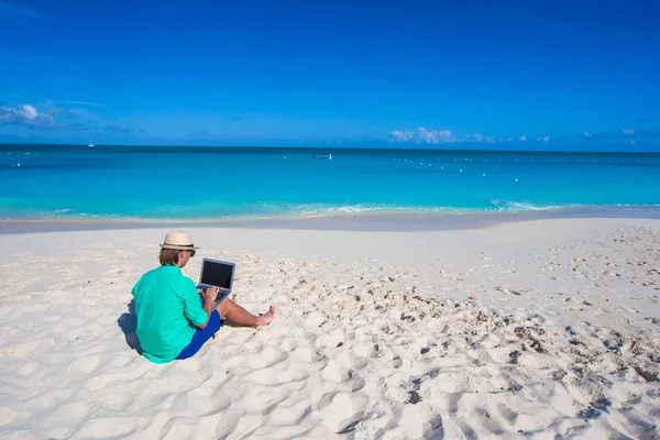 Young man with laptop on background of turquoise ocean — Stock Photo, Image